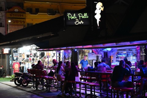 A busy open-front bar lit with neon at night
