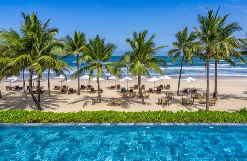 Palm trees, sun loungers and a pool on My Khe Beach, Da Nang