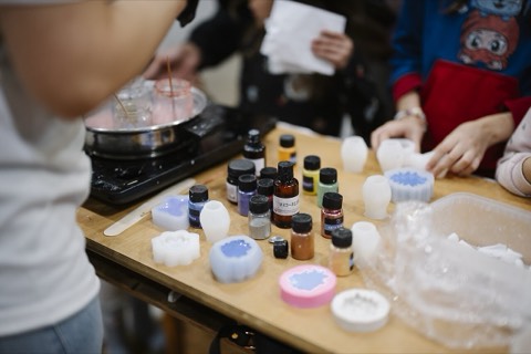 Hands at a workshop table covered with craft materials and molds