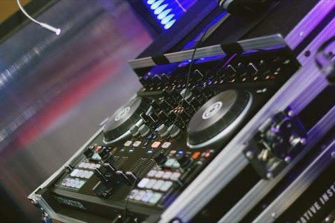 Close-up of a DJ controller with illuminated buttons and jog wheels