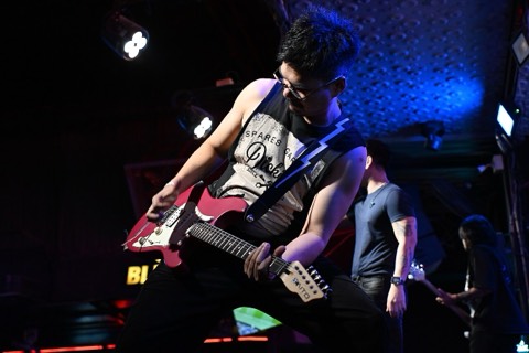 A guitarist leaning into a solo under blue stage lights