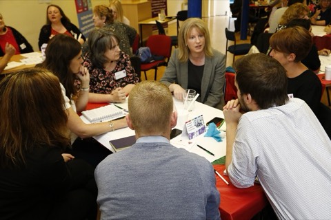 People talking around tables at a community meeting