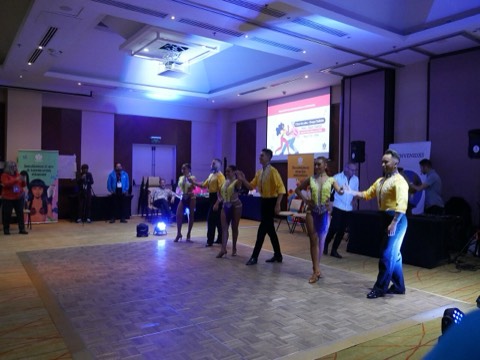 Couples dancing salsa on a hall dance floor under colored lights