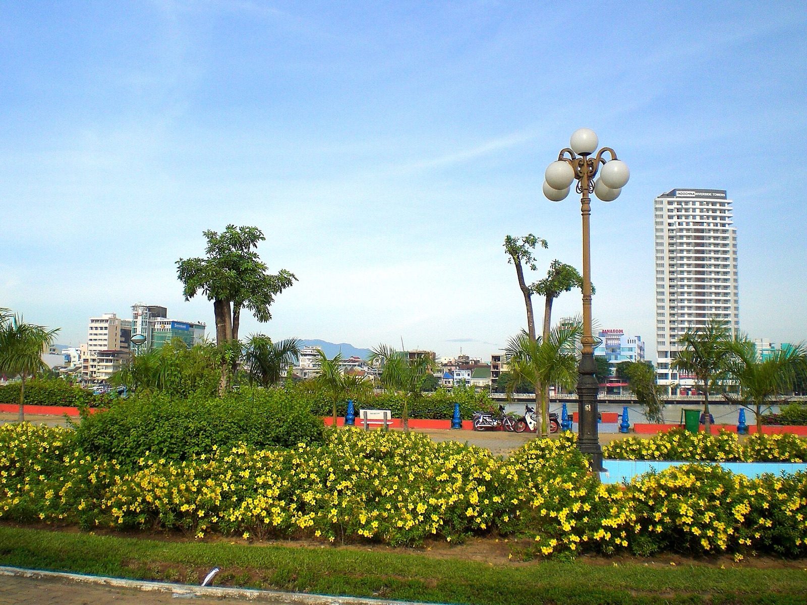 A finished, landscaped stretch of the Bach Dang riverfront walkway with palms, flowers and lamp posts