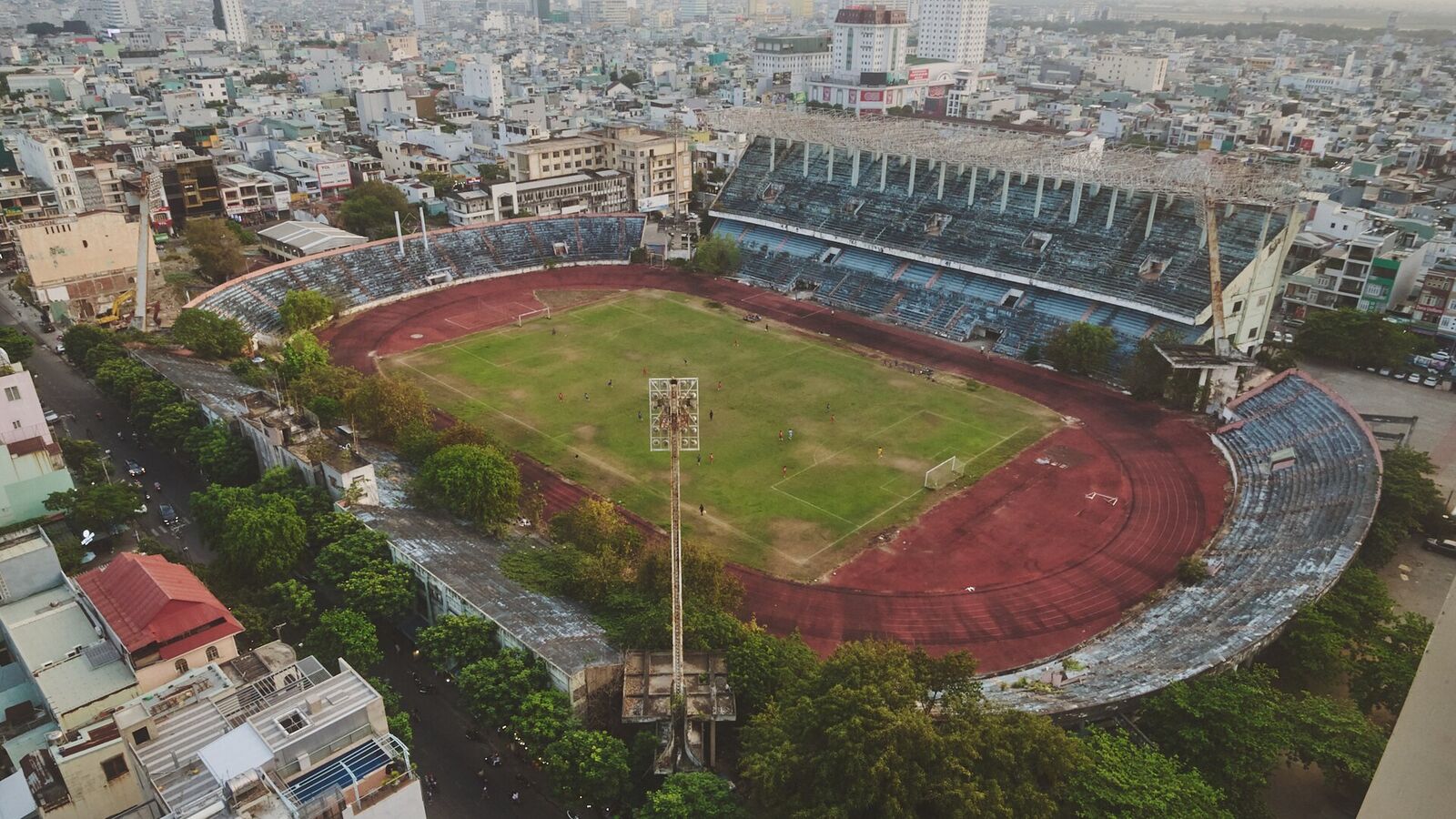 Aerial view of Chi Lăng Stadium in Da Nang: a grass pitch inside a red running track, with stands and surrounding buildings