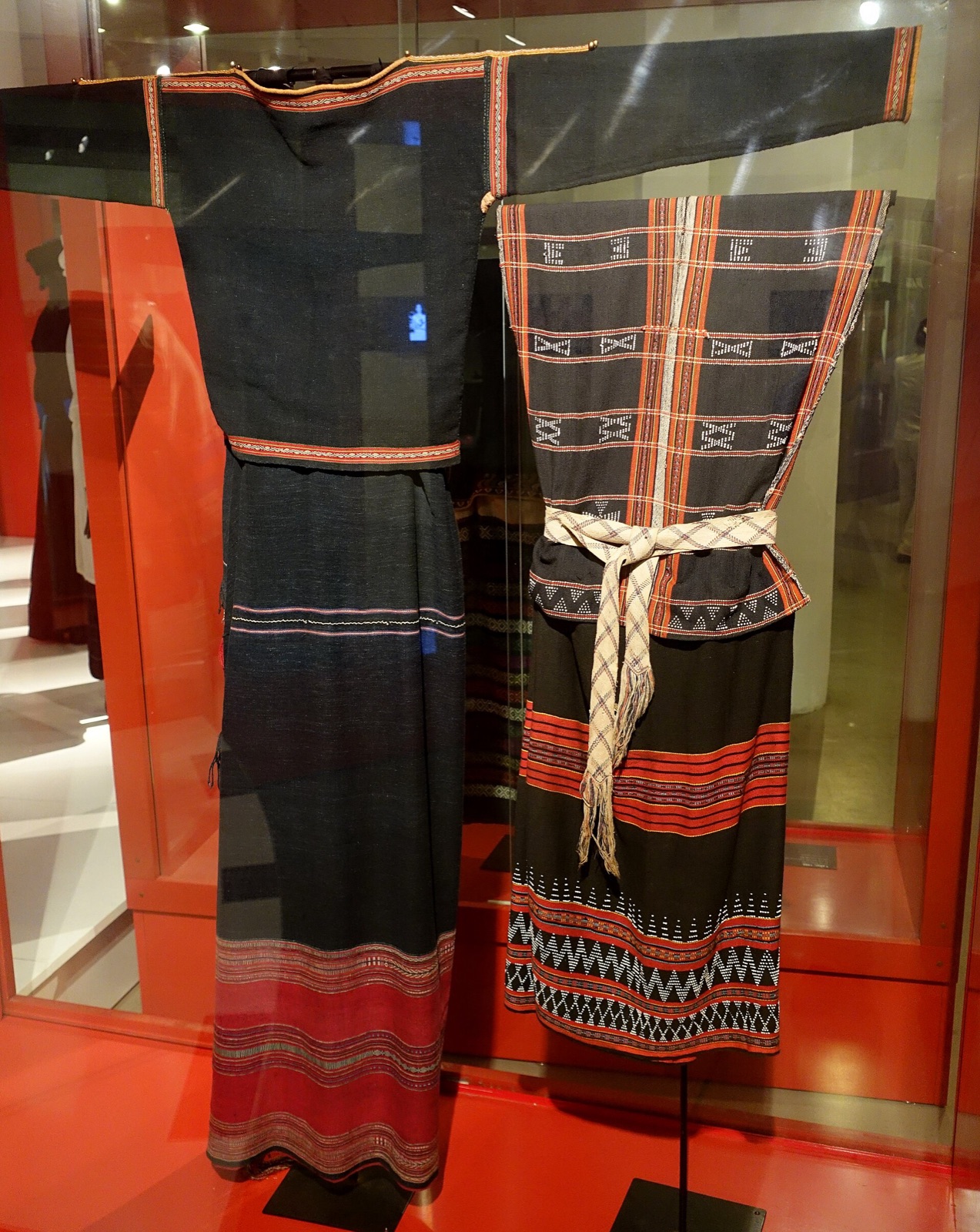 Traditional handwoven Co Tu clothing with indigo cloth and beadwork displayed in a museum case
