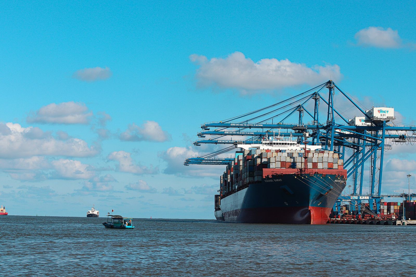 A large container ship moored at a container terminal with cranes