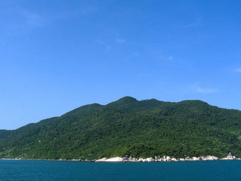 Turquoise water and a rocky green island shoreline at Cu Lao Cham marine park