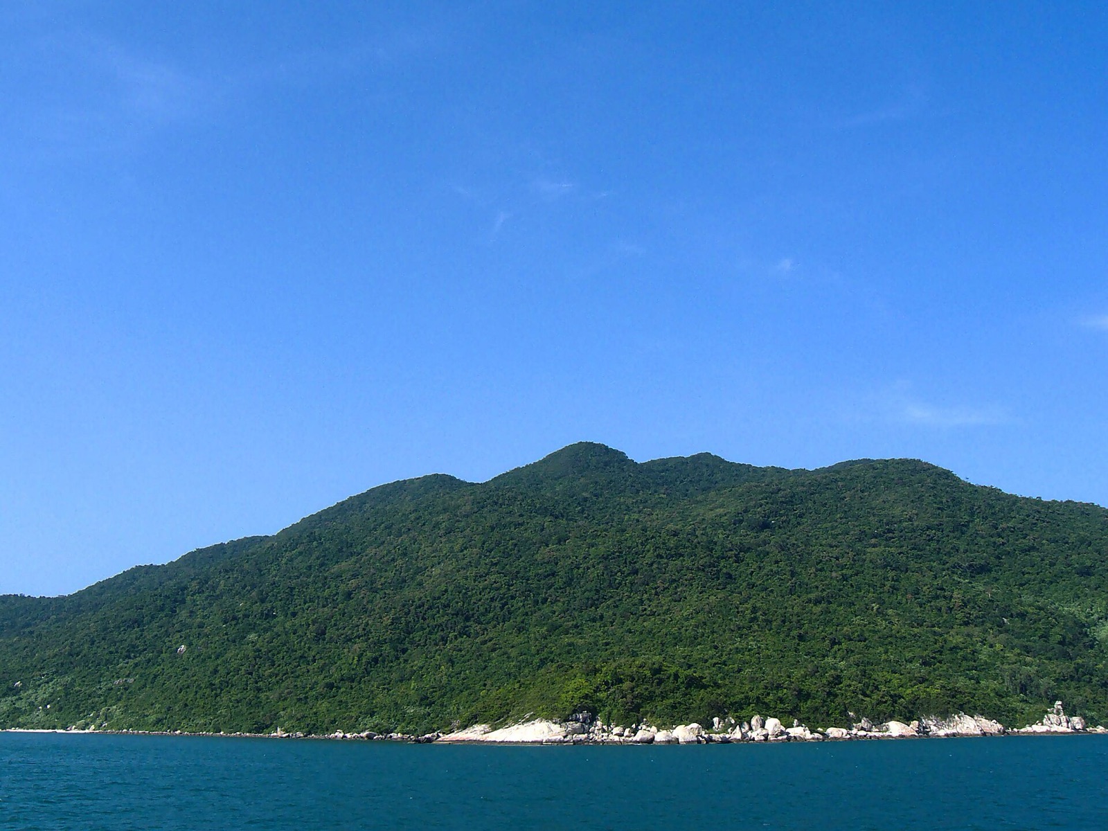 Turquoise water and a rocky green island shoreline at Cu Lao Cham marine park