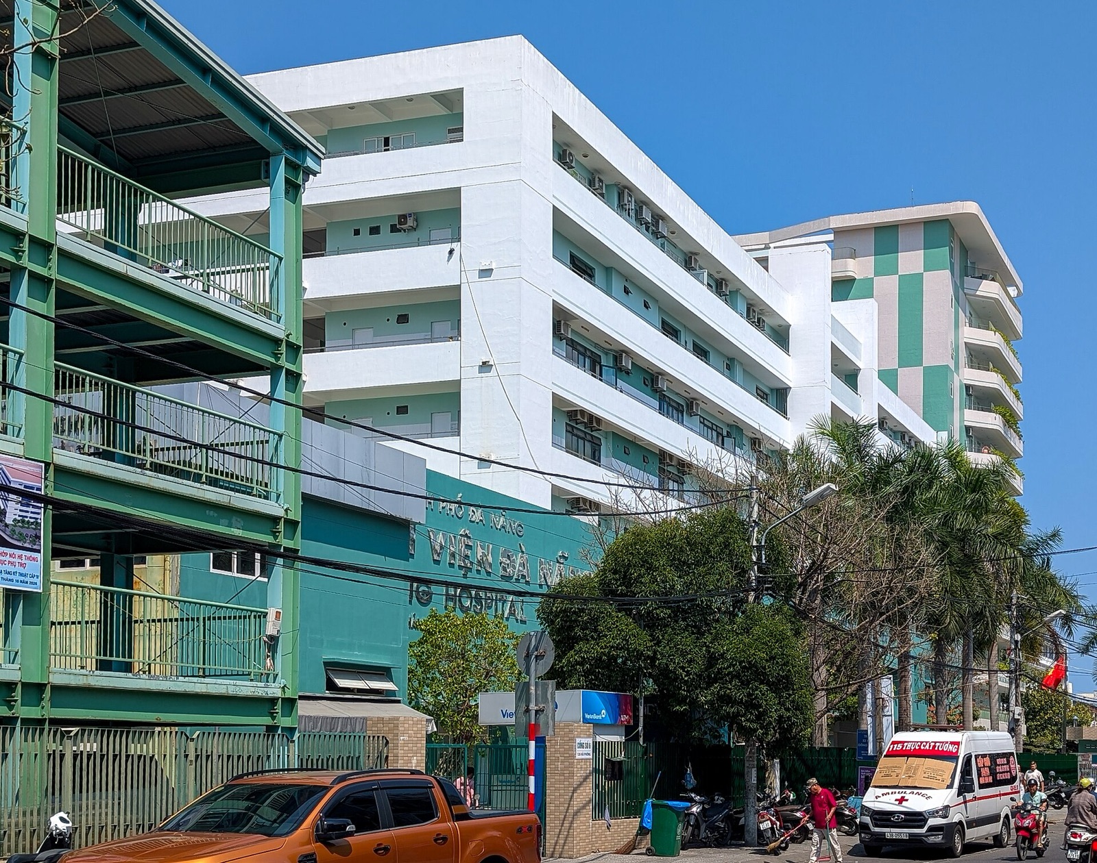 The multi-story main building of Da Nang Hospital with balconies and trees along the street