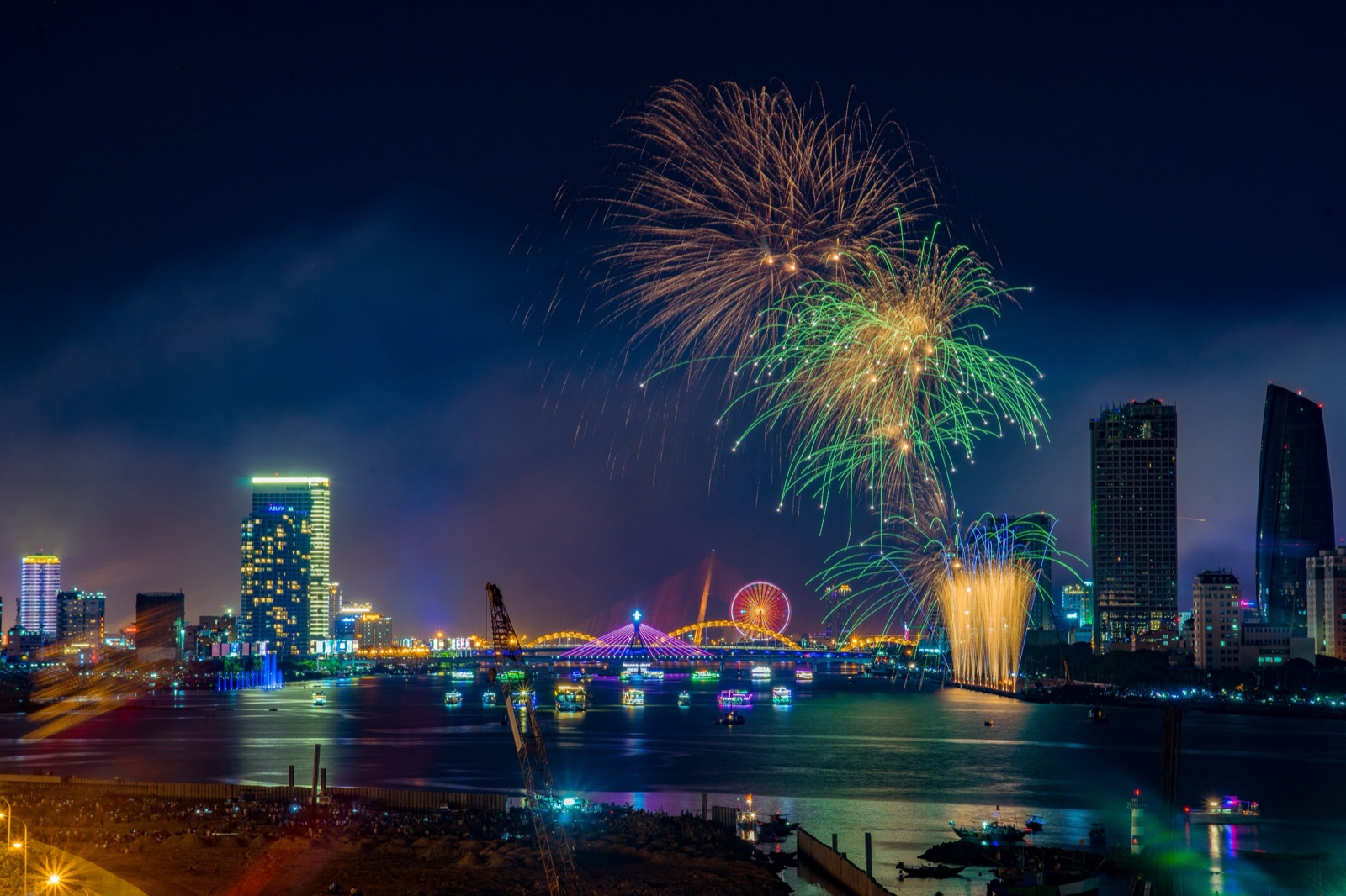 Fireworks bursting over the Han River at night with Da Nang's lit-up high-rises along the bank