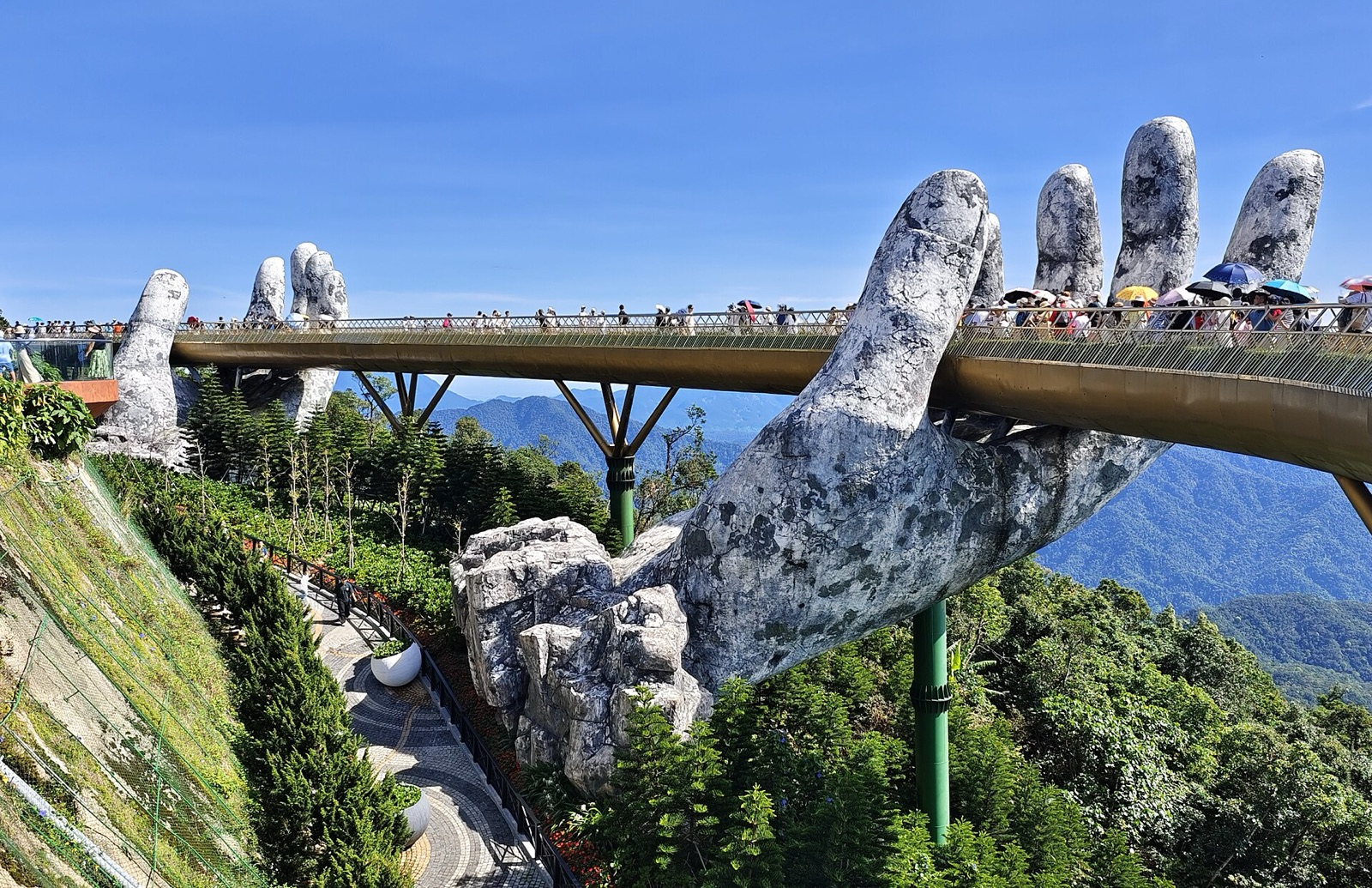 The Golden Bridge at Ba Na Hills, a gold walkway held up by two giant stone hands, with visitors walking along it