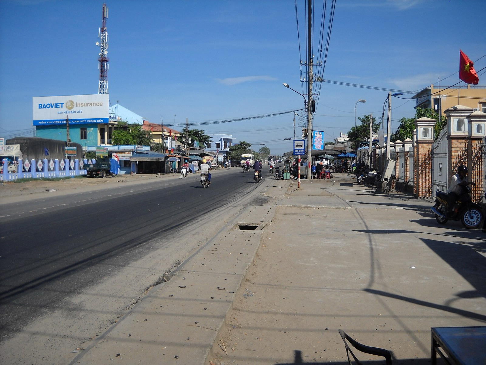 The main road through Hà Lam town in the former Thăng Bình district, with shops, a billboard and motorbikes