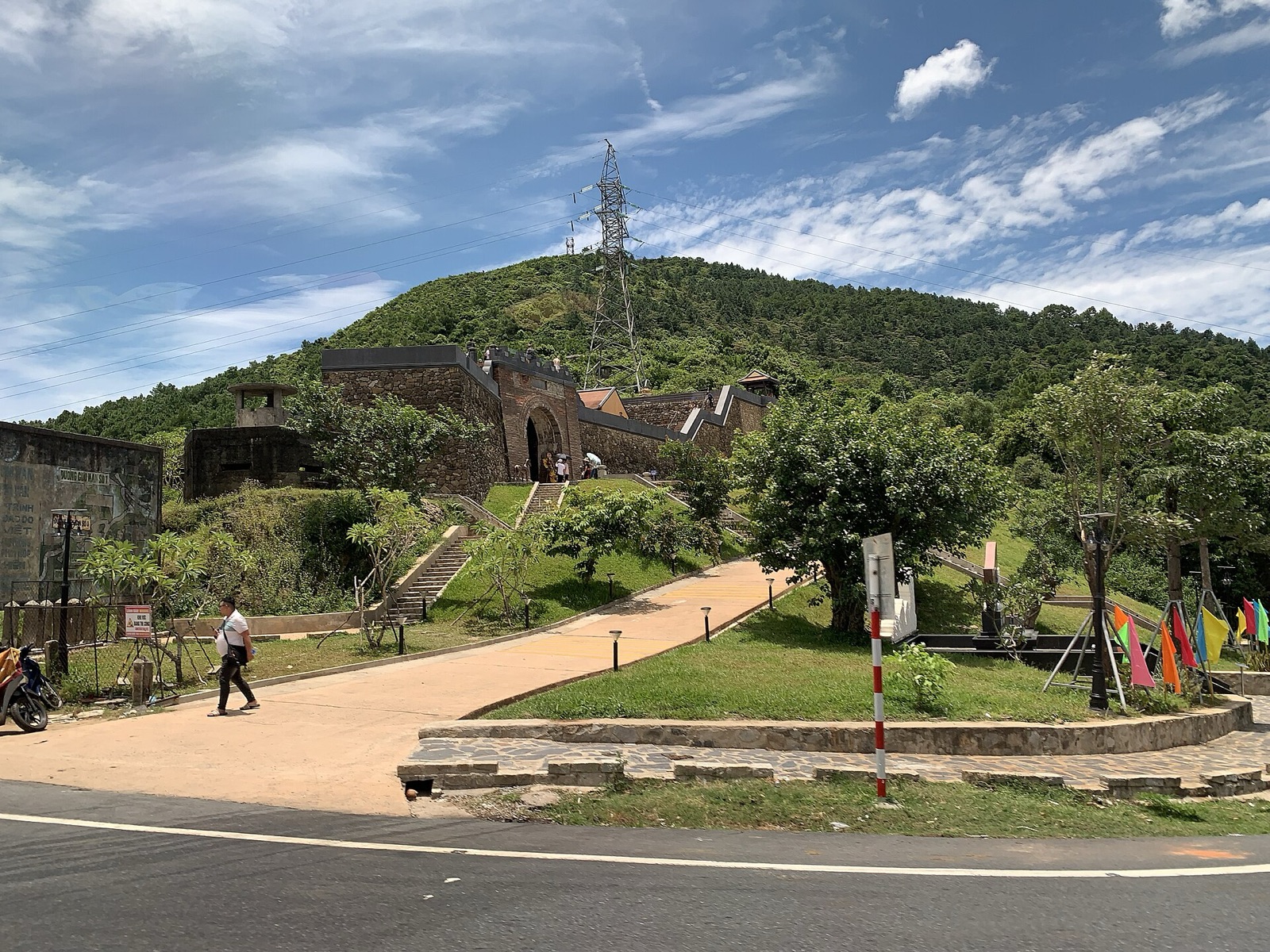 The restored stone fortress of Hai Van Quan at the top of Hai Van Pass, with green lawns, a path and wooded hills behind