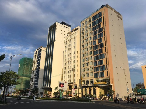 Tall hotel towers lit by afternoon sun along a street in Da Nang