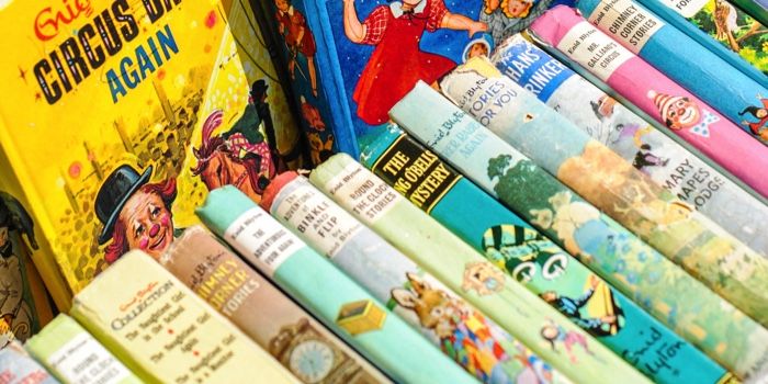 Colorful children’s books lined up on their sides with their spines and covers facing up