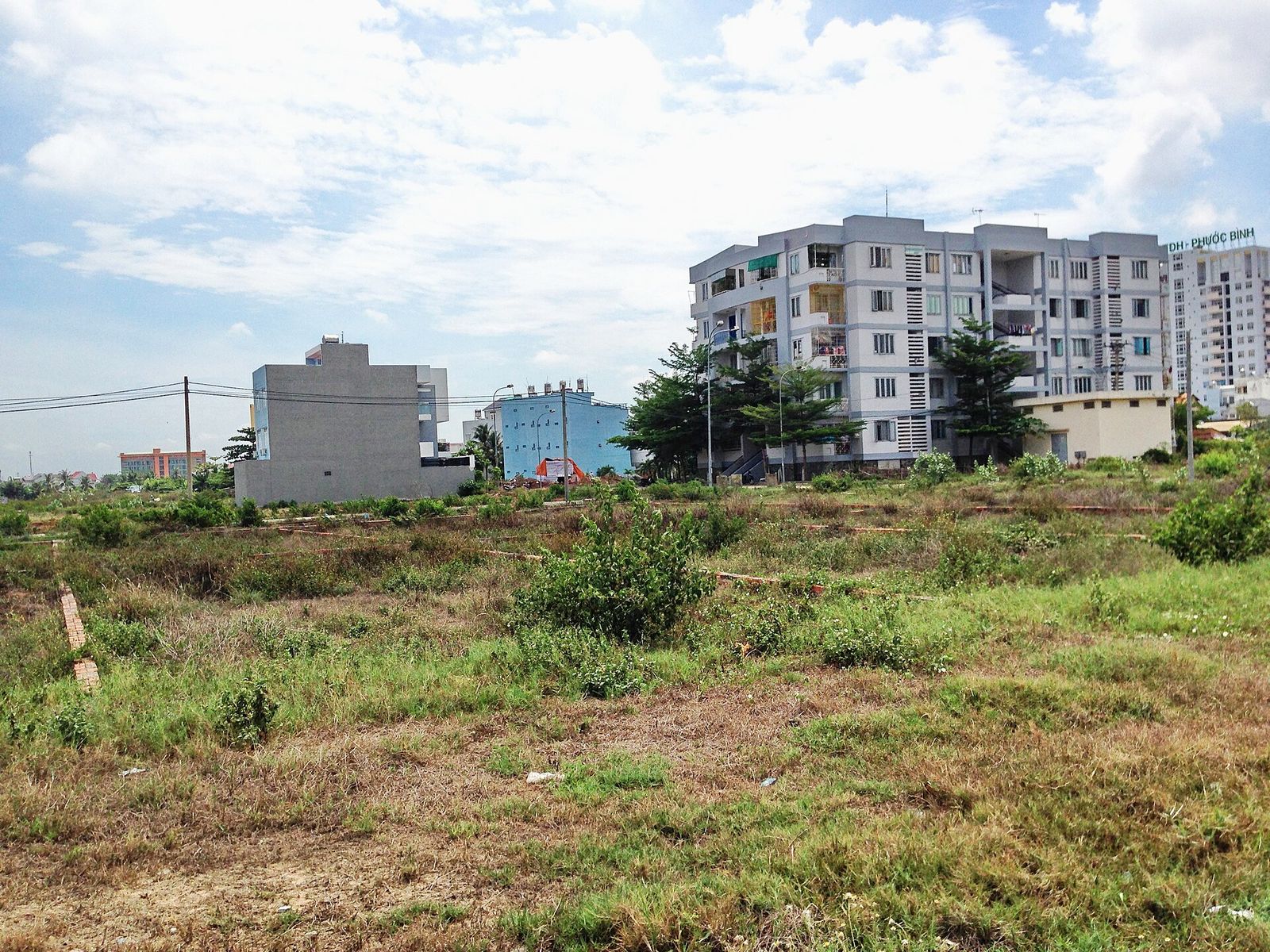 A newly built mid-rise apartment block at the edge of an empty, grassy lot