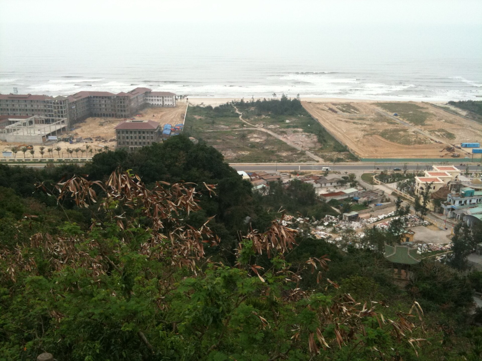 Hillside view over a coastal strip near Non Nuoc beach with resort buildings under construction, bare lots and the sea beyond