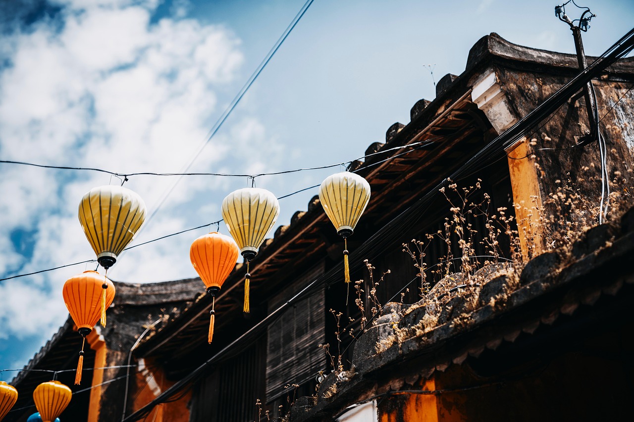 Yellow and orange silk lanterns hanging above the tiled roofs of old houses in Hội An