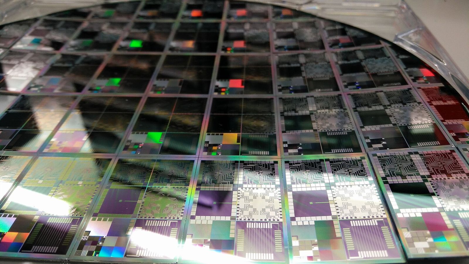Close-up of a silicon wafer covered in a grid of iridescent microchips