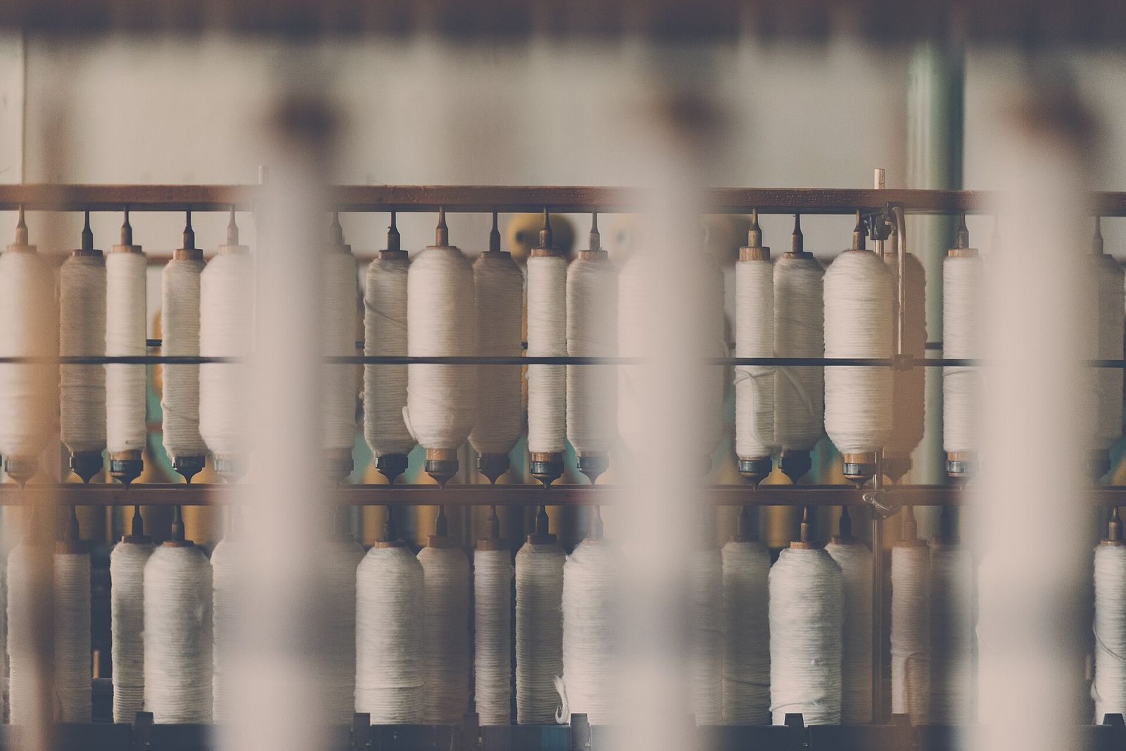 Rows of white thread spools on spindles in a textile machine